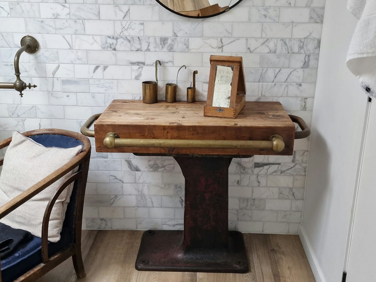 Wooden pedestal washbasin against a white brick-effect wall.