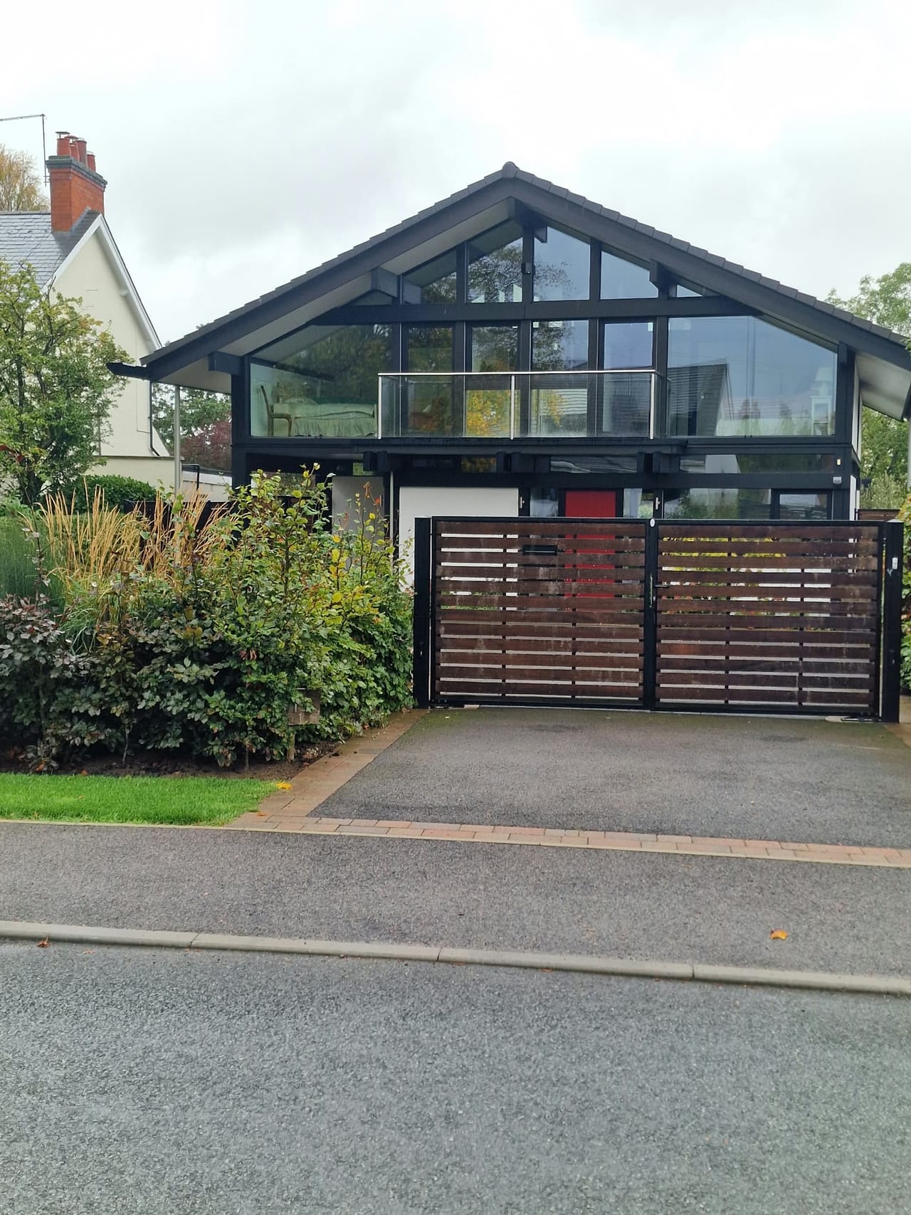 House frontage with a broad glazed gable, brickwork and a gated driveway.