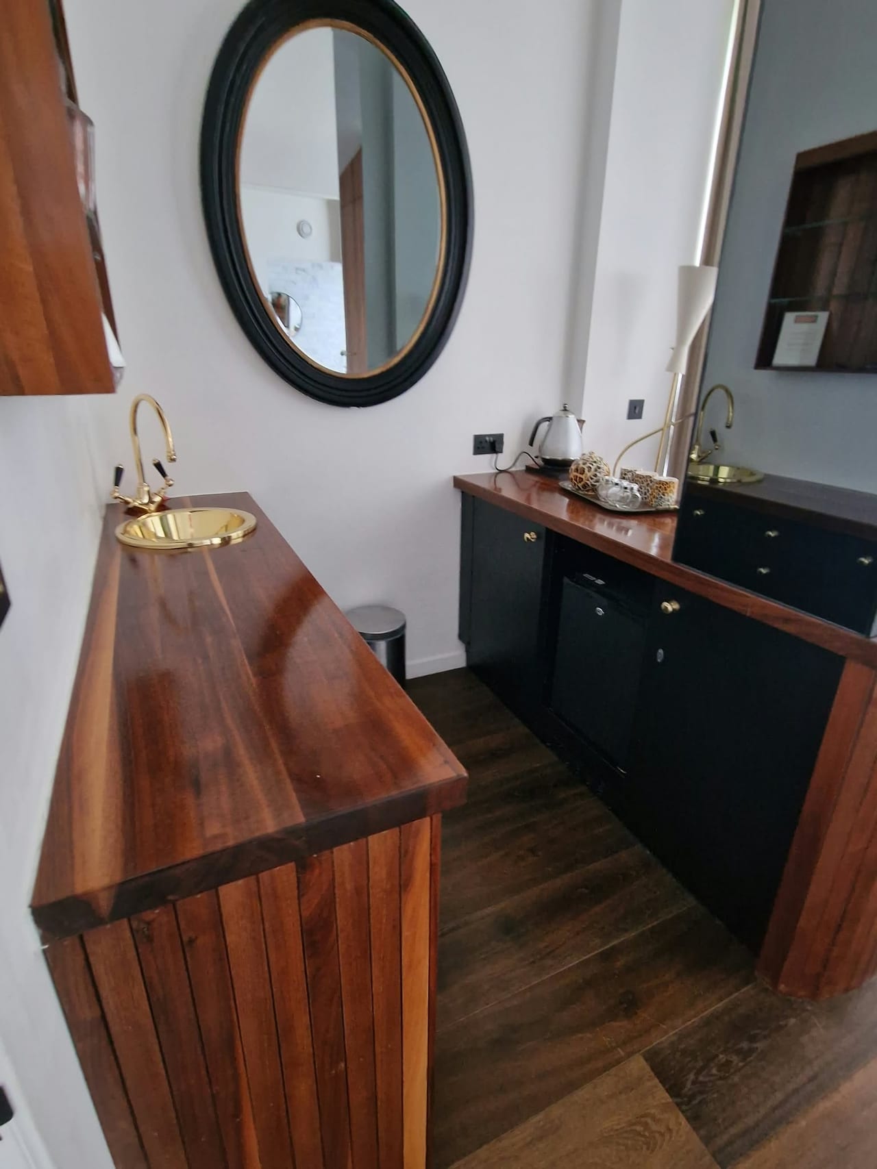 Bathroom interior with a wooden counter, round mirror and dark green basin cabinet.